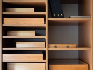 A wooden wall shelf with various things organized within it.