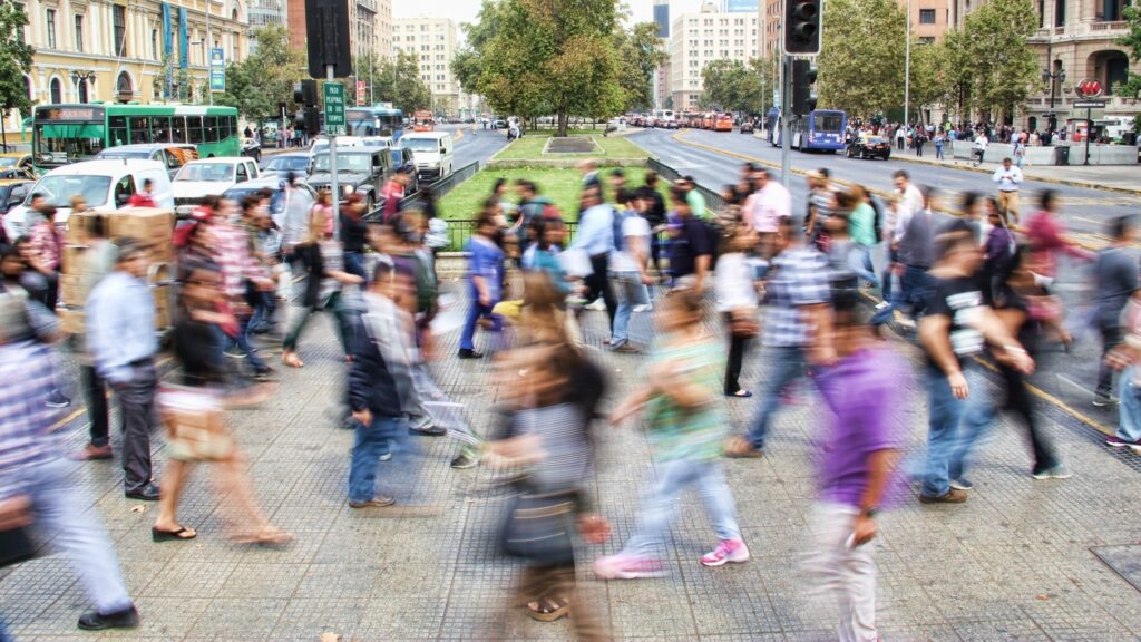 A busy street crosswalk with a crowd of people motion blurred.