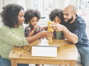 A family does crafts on a table in their home.