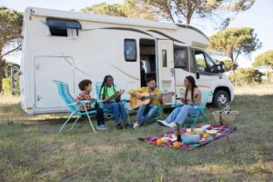 a family sits outside their trailer singing songs and eating snacks