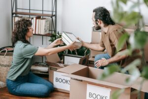 A woman and man sit in their living room sorting through old books.