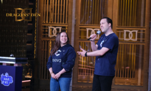 eeva Co-Founders Adrienne and Jarrod pitch in the Dragons' Den. Jarrod holds the mic while Adrienne looks towards him smiling.