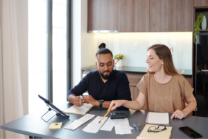 A man and woman sit at a kitchen table looking at receipts, doing the household budgeting.