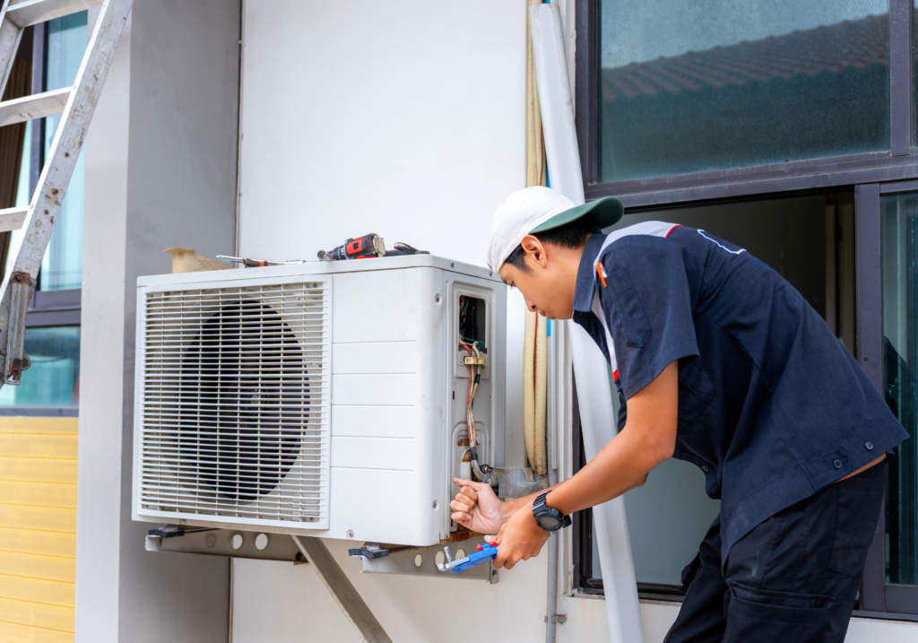 main repairing AC unit at window of home